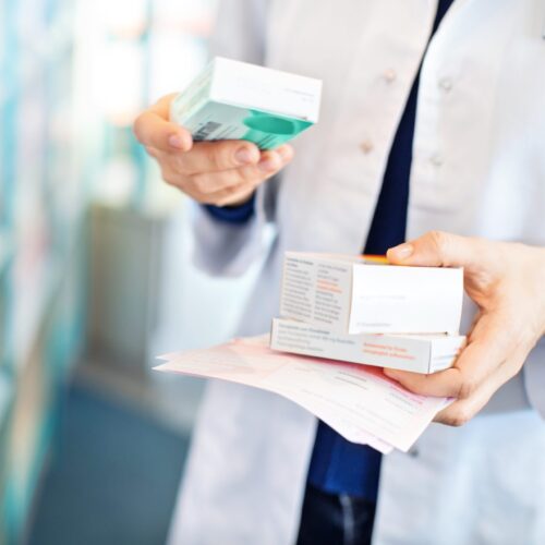 Closeup of pharmacist's hands taking medicines from shelf at the pharmacy