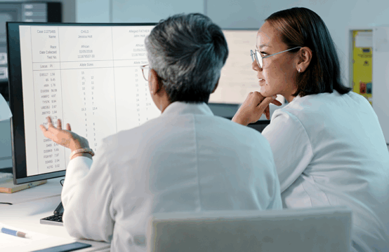 Zwei Wissenschaftlerinnen analysieren Patientendaten am Computer © istockphoto.com/Kobus Louw 1483251775 Zwei Wissenschaftlerinnen in weißen Kitteln sitzen vor einem Computerbildschirm und analysieren Patientendaten aus der regionalen Routineversorgung.